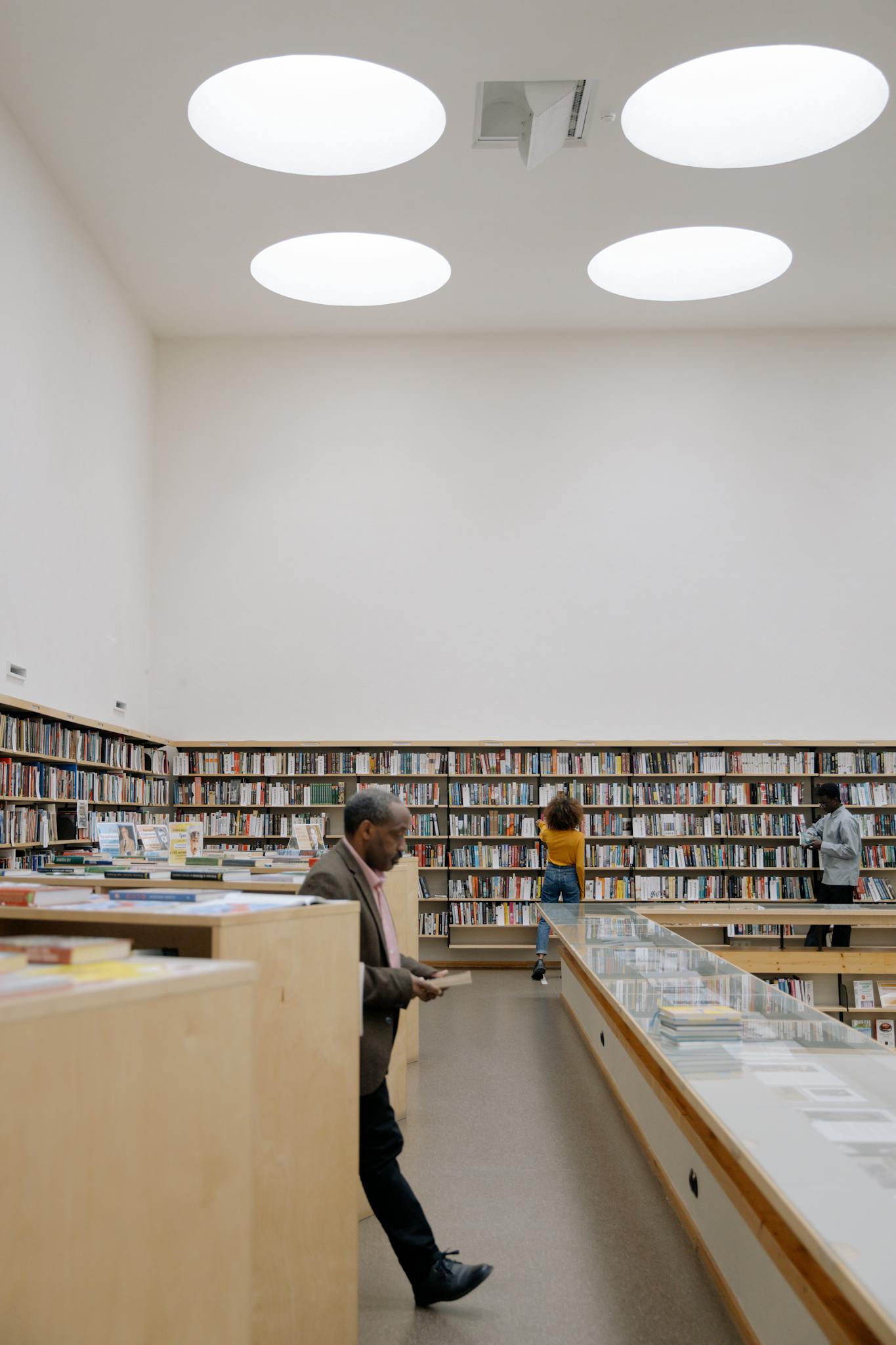 A diverse group of adults exploring a spacious public library with modern lighting.